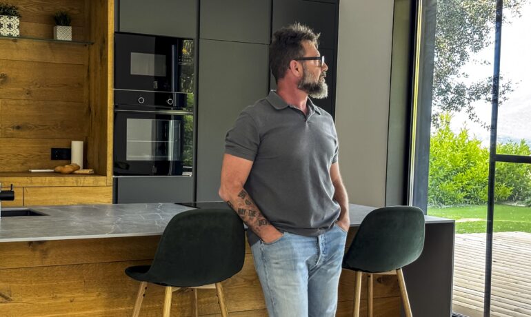 Mann steht nachdenklich in seiner Küche und blickt aus dem Fenster – Sinnbild für eine innere Verstimmung, die von außen nicht sichtbar ist